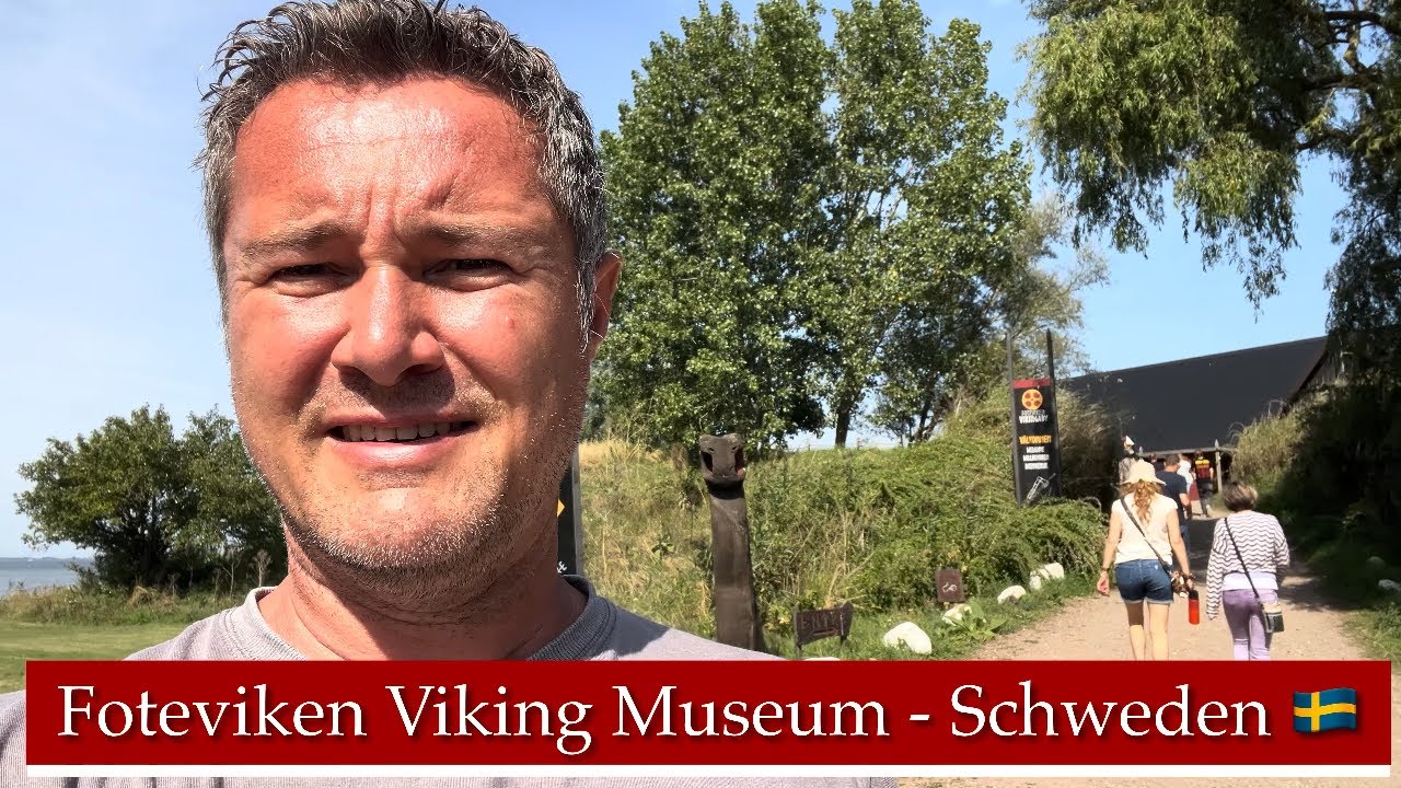 Mann vor Foteviken Viking Museum in Schweden mit Besuchern auf dem Weg zum Eingang.