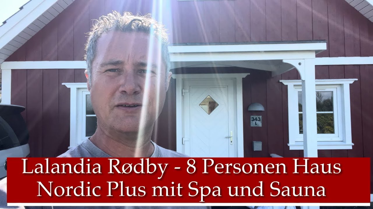 Mann vor rotem Haus mit weißer Tür und Fenstern; Textfeld unten zeigt „Lalandia Rødby - 8 Personen Haus Nordic Plus mit Spa