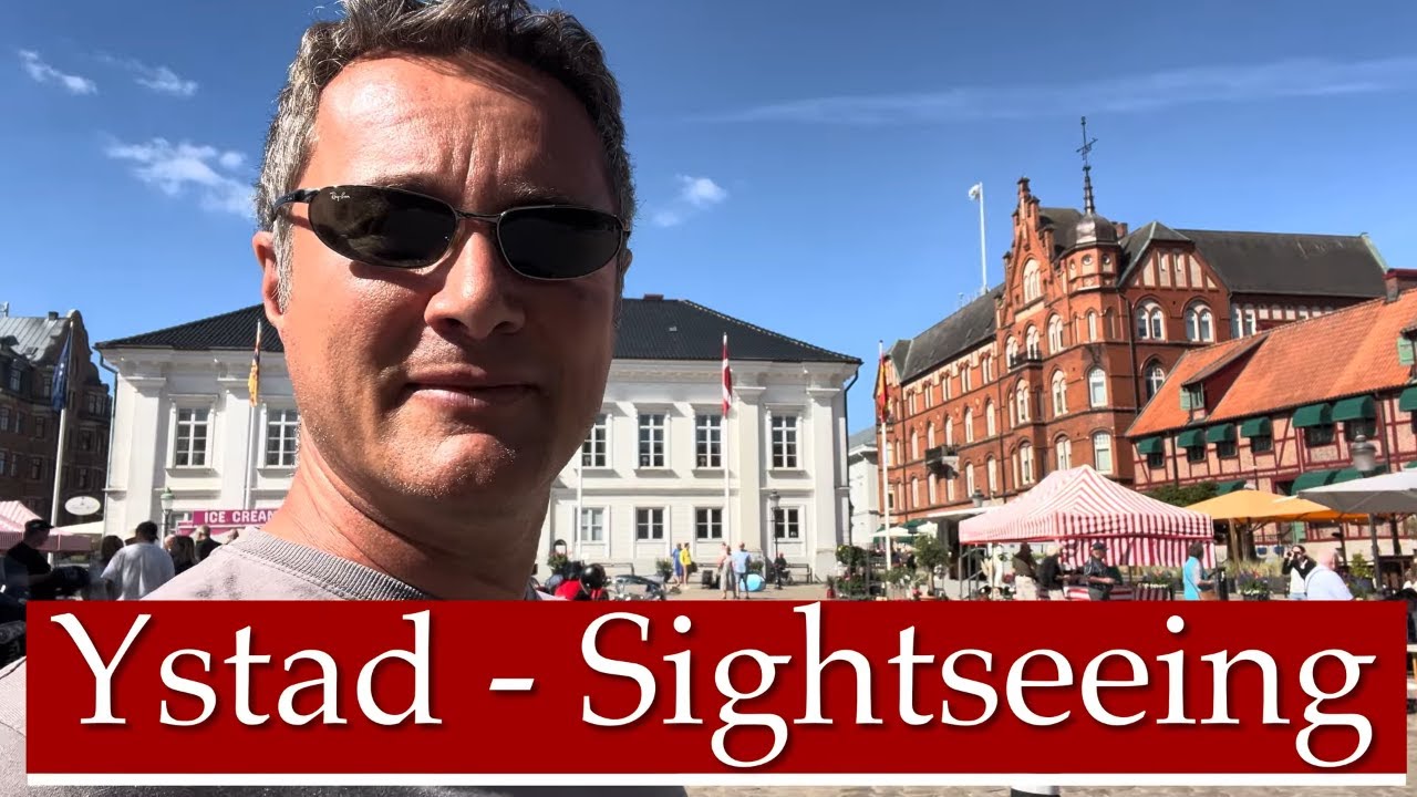 Mann mit Sonnenbrille vor historischen Gebäuden in Ystad unter blauem Himmel